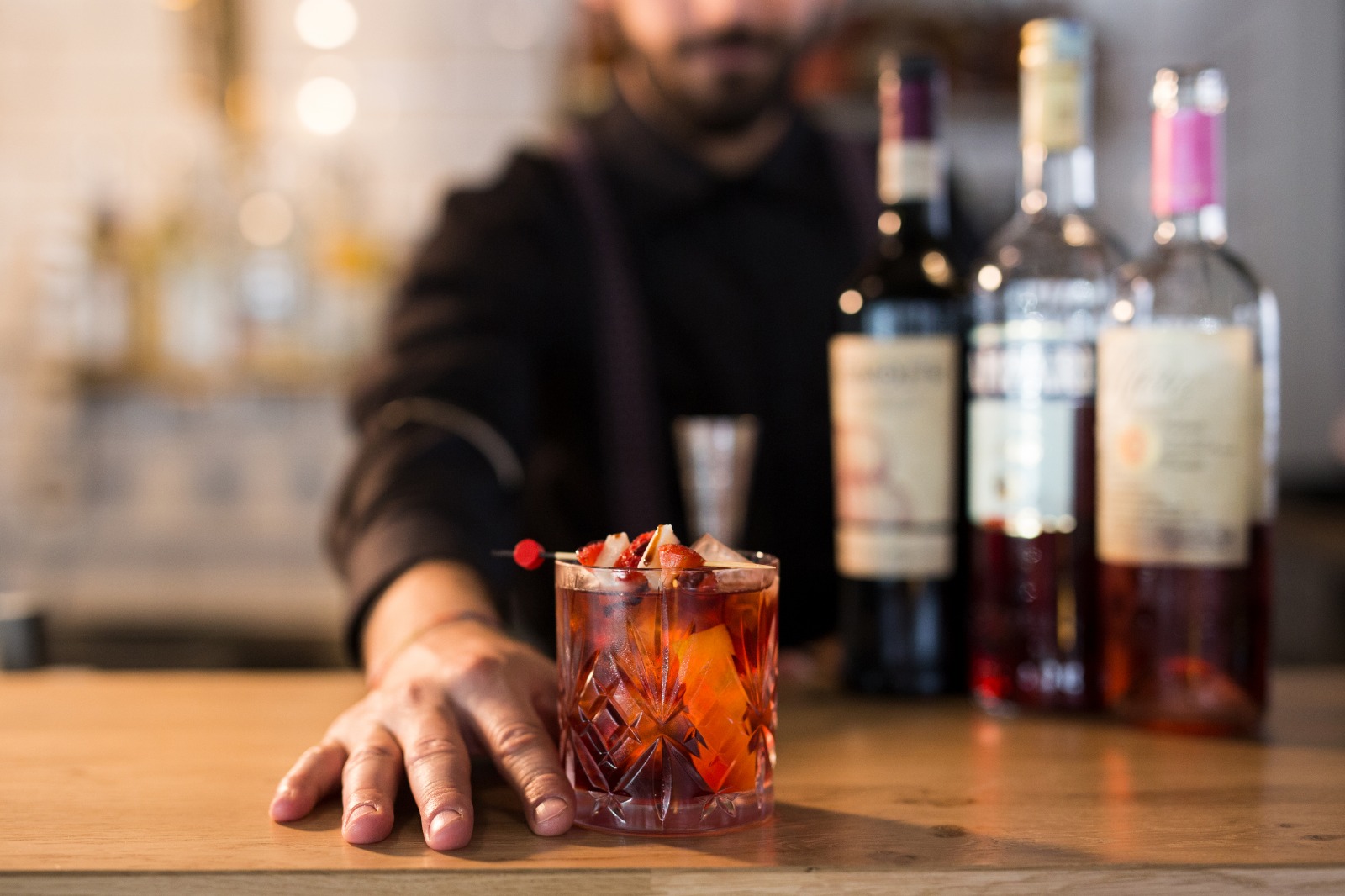 Il bancone bar la sera, con un cocktail appena preparato in primo piano