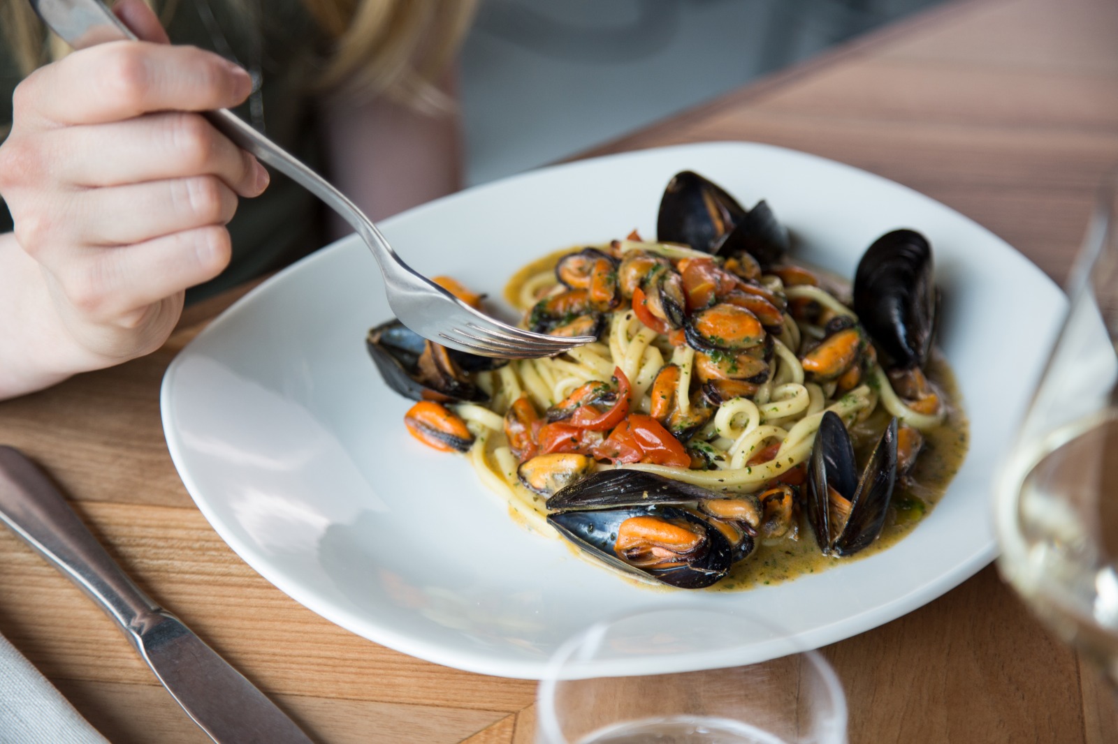 Piatto di linguine con cozze al pomodoro e prezzemolo, servito al tavolo
